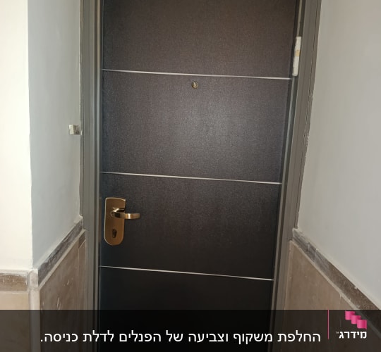 דלת חומה עם ידית זהב במסגרת אפורה